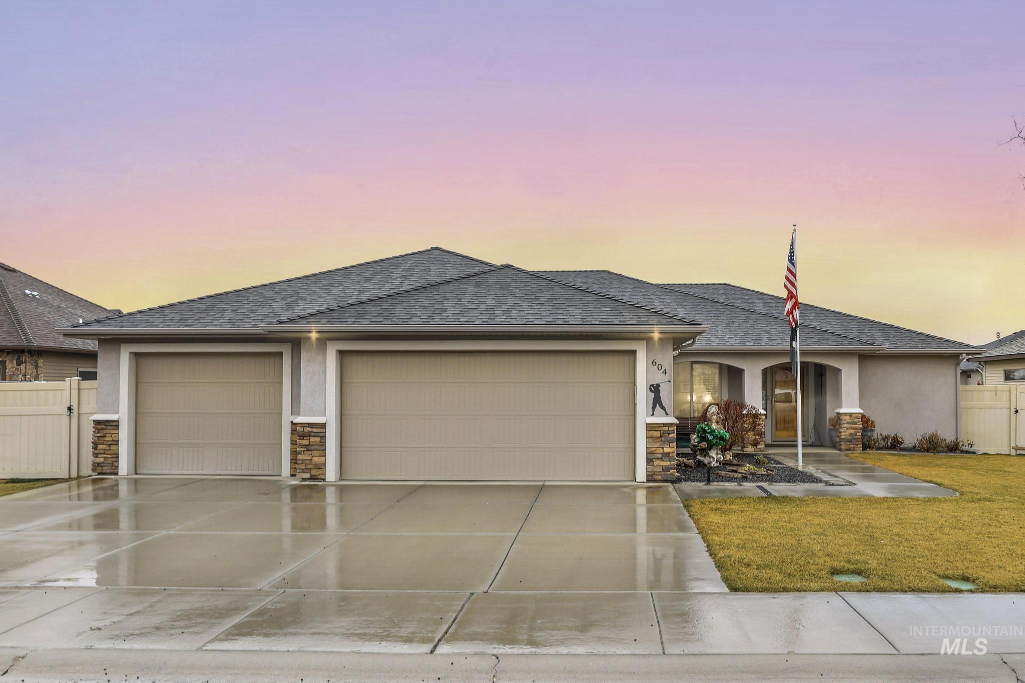 View of front of home with stucco siding, stone siding, an attached garage, and driveway