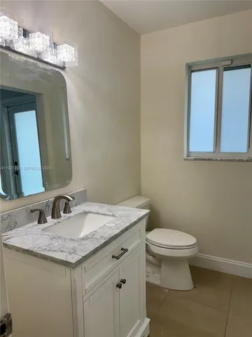a bathroom with a granite countertop sink a toilet and a mirror
