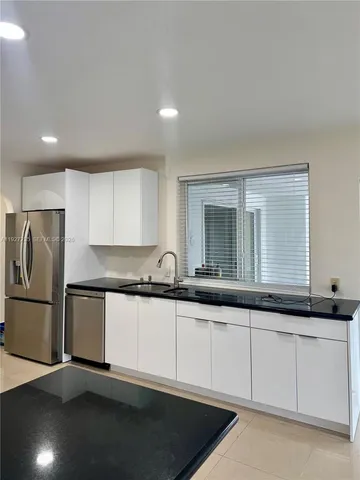 a kitchen with granite countertop white cabinets and a refrigerator