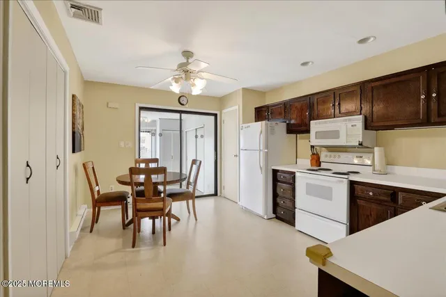 a kitchen with stainless steel appliances kitchen island granite countertop a dining table chairs refrigerator and cabinets