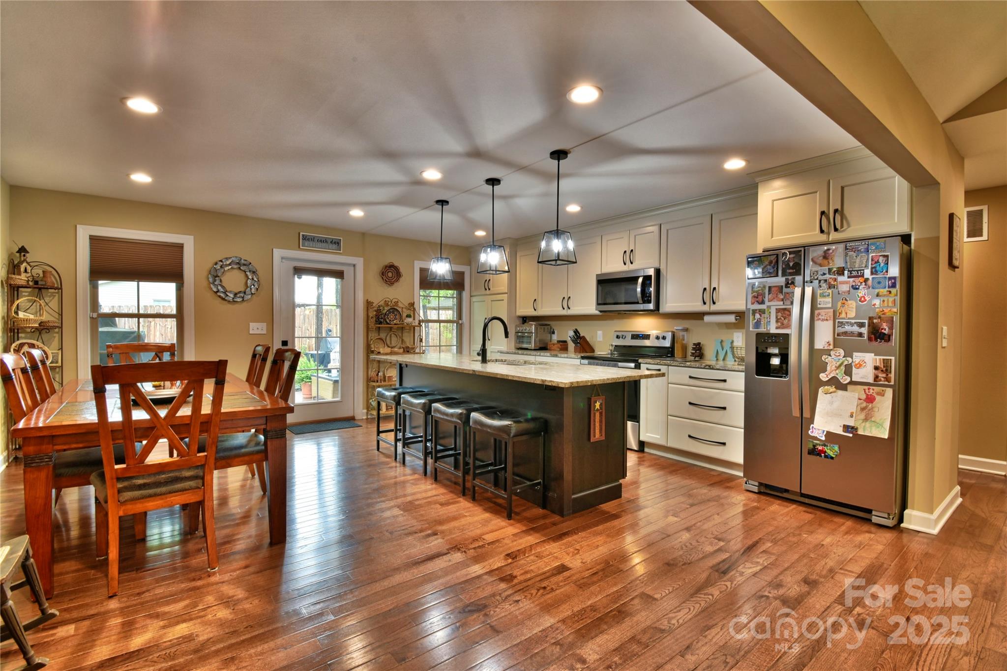 482 Old Camp Road Denton, NC 27239 - Photo 13 of 48 a kitchen with stainless steel appliances kitchen island granite countertop a stove top oven a refrigerator a dining table and chairs with wooden floor