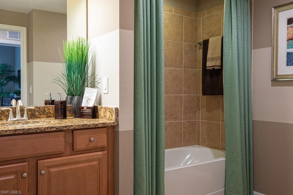 3161 Aviamar Circle, Unit 101 Naples, FL 34114 - Photo 12 of 32 a bathroom with a granite countertop sink a mirror and a bathtub