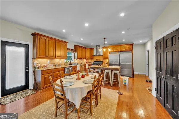 a dining room with stainless steel appliances kitchen island granite countertop a dining table chairs and granite counter top