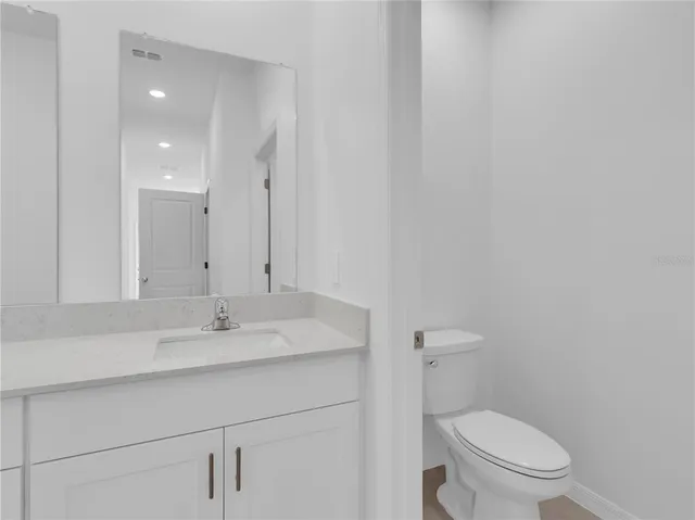 a bathroom with a toilet a sink a mirror and vanity