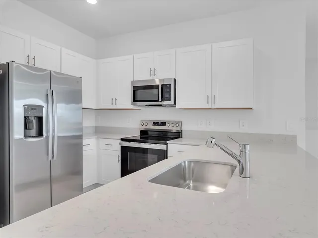 a kitchen with stainless steel appliances granite countertop a refrigerator sink and microwave