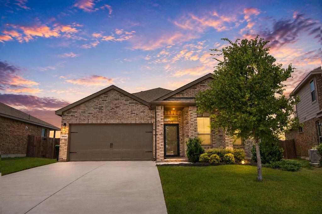 1804 Mensa Drive Haslet, TX 76052 - Photo 2 of 30 Brick facade with a two-car garage, concrete driveway, and a front entry with sidelights