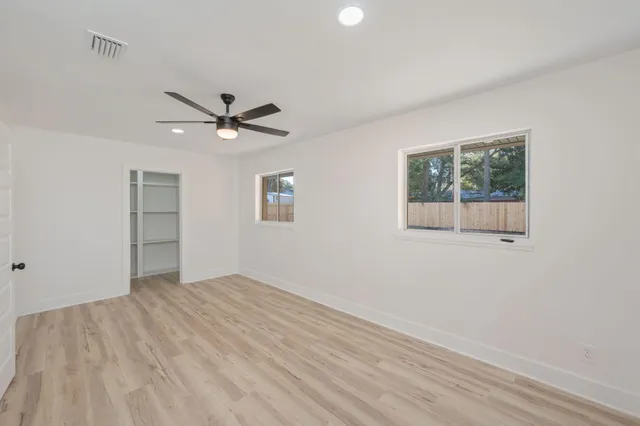 an empty room with a ceiling fan and wooden floor