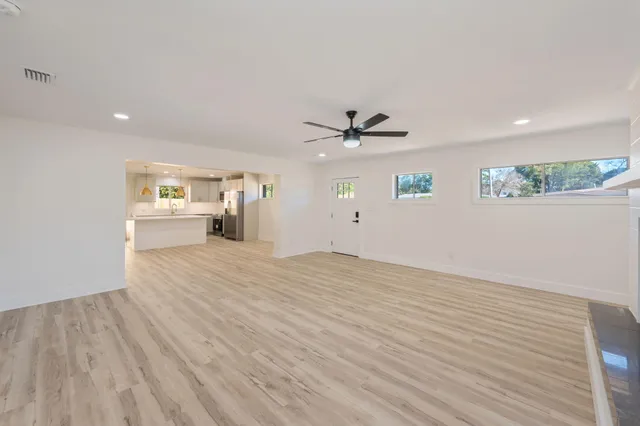 a large white kitchen with a refrigerator a stove a microwave and a dining table with wooden floor