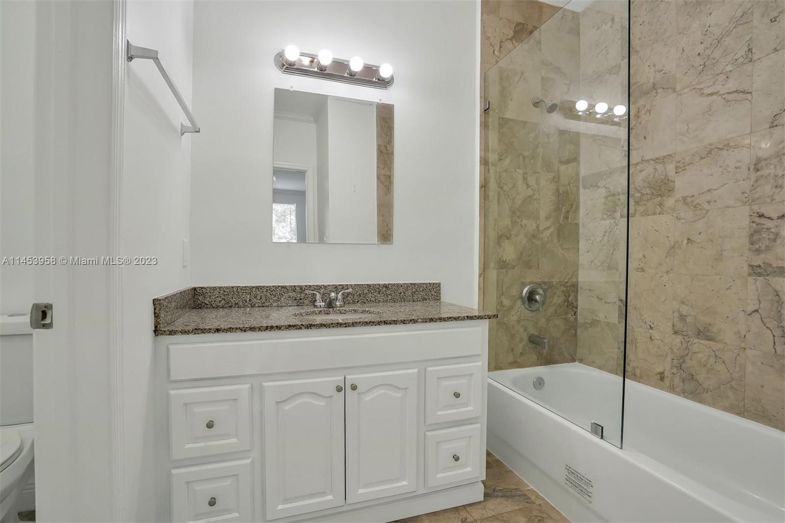 3012 Elizabeth Street, Unit 3012 Miami, FL 33133 - Photo 12 of 27 a bathroom with a granite countertop sink a mirror a bathtub and shower