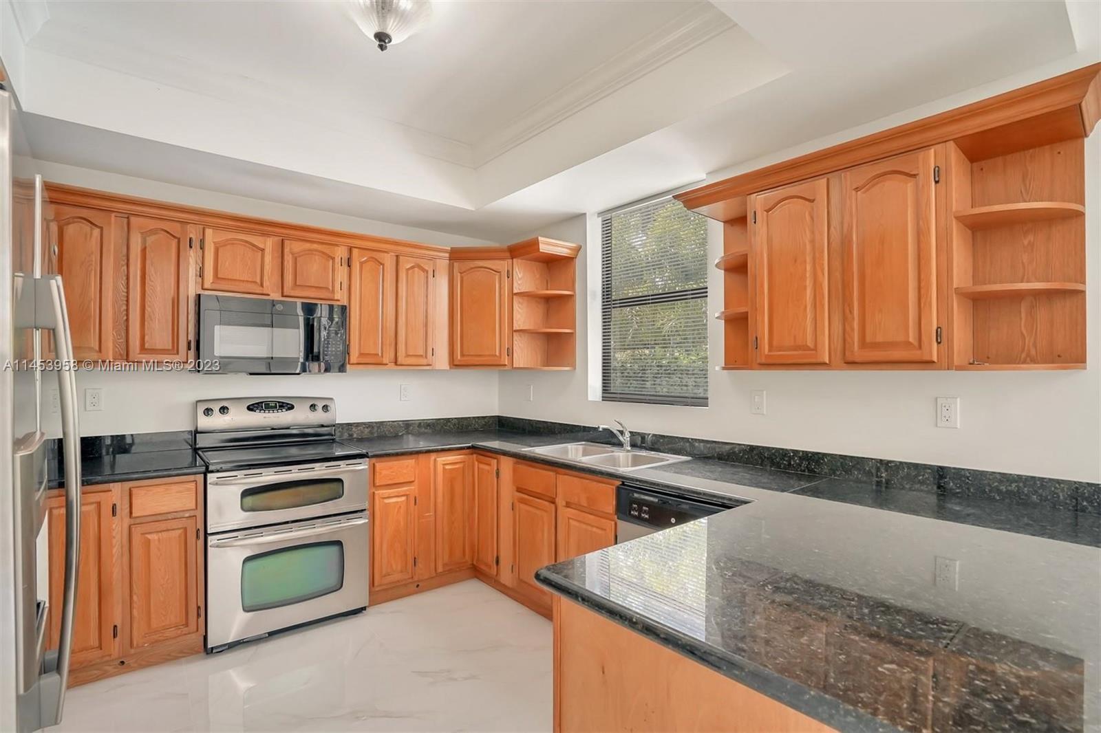 3012 Elizabeth Street, Unit 3012 Miami, FL 33133 - Photo 3 of 27 a kitchen with stainless steel appliances granite countertop wooden cabinets a stove and a sink