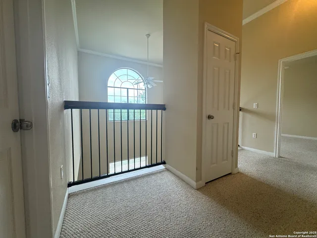 an empty room with a chandelier fan and windows