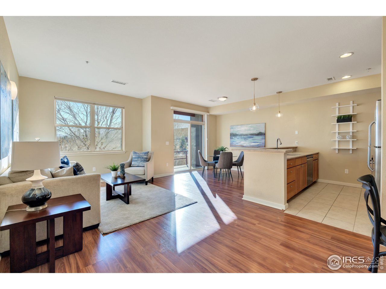 a living room with furniture dining table wooden floor and a large window