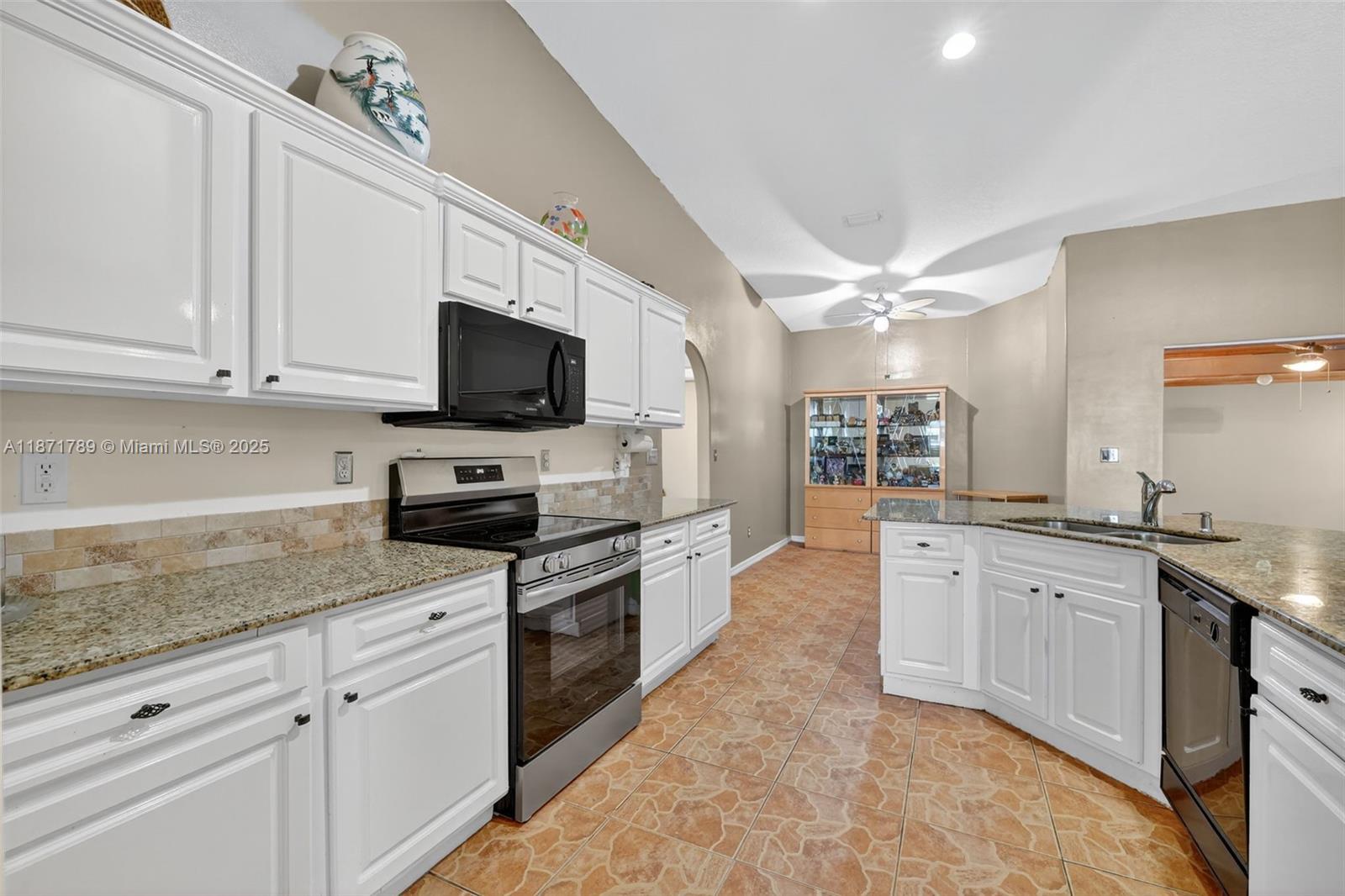 1019 Southwest California Boulevard Port St. Lucie, FL 34953 - Photo 14 of 40 a large kitchen with granite countertop a stove top oven a sink a dining table and chairs