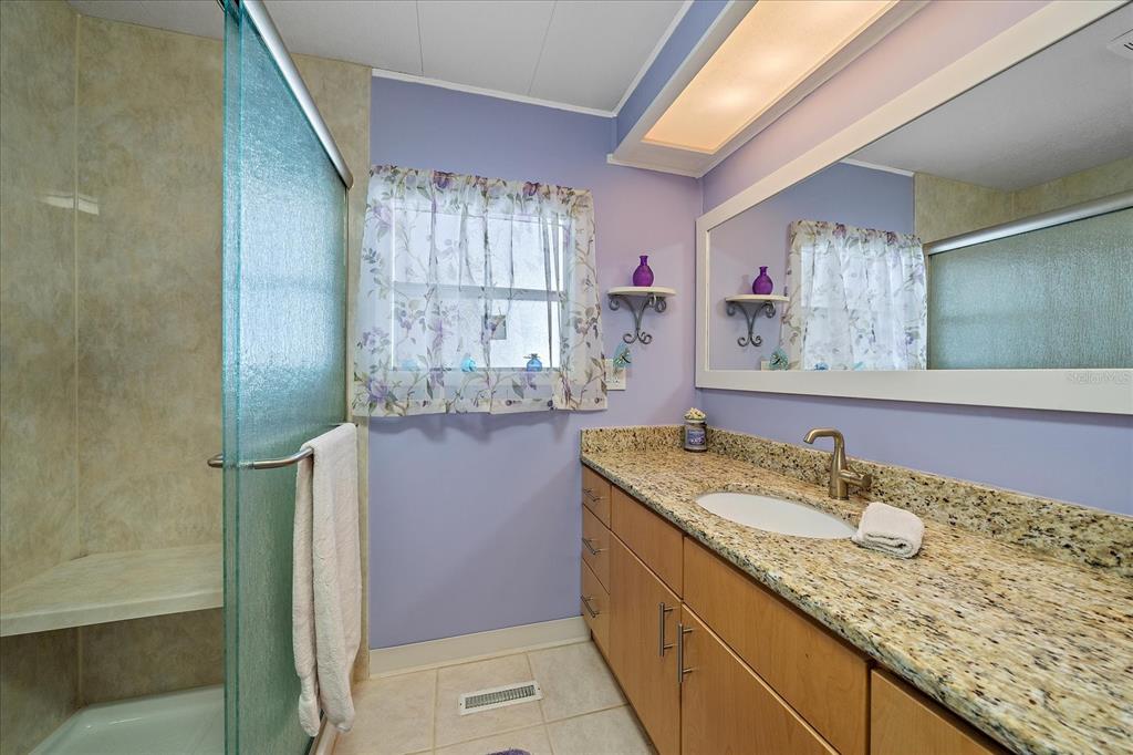 521 Roma Road Venice, FL 34285 - Photo 28 of 57 a bathroom with a granite countertop sink a mirror and a shower