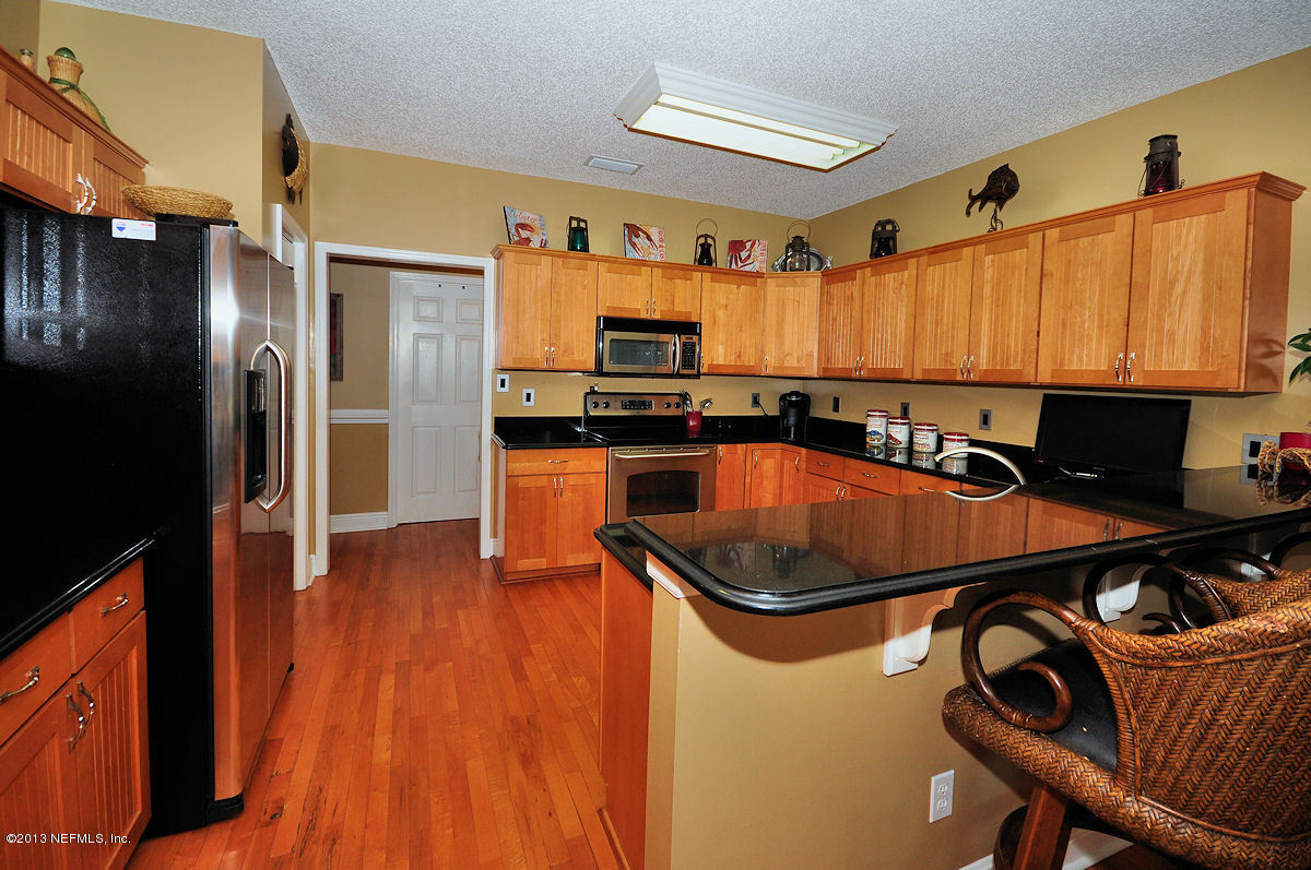 16024 Shellcracker Road Jacksonville, FL 32226 - Photo 7 of 26 a kitchen with stainless steel appliances granite countertop a refrigerator a sink dishwasher a stove and a dining table with wooden floor