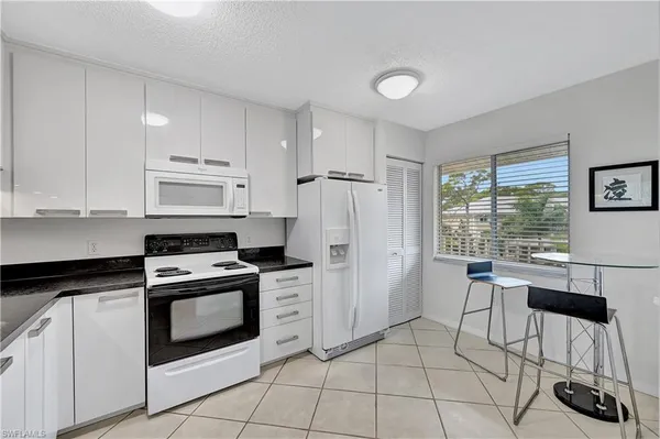 a kitchen with granite countertop white cabinets and white appliances