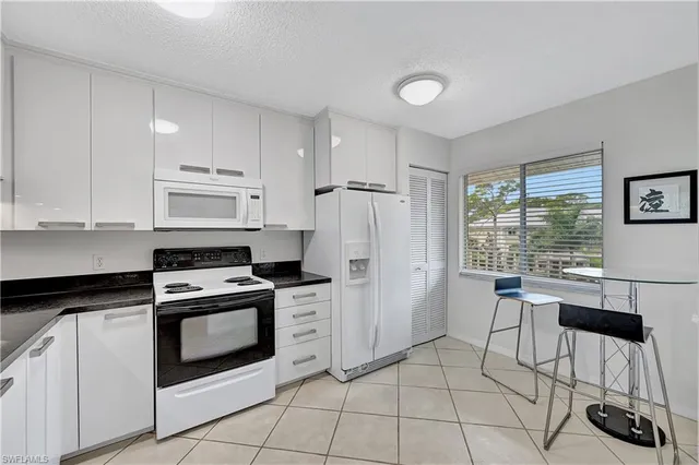 a kitchen with granite countertop white cabinets and white appliances