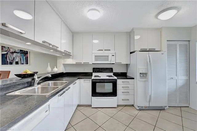 a kitchen with granite countertop a sink stove and refrigerator