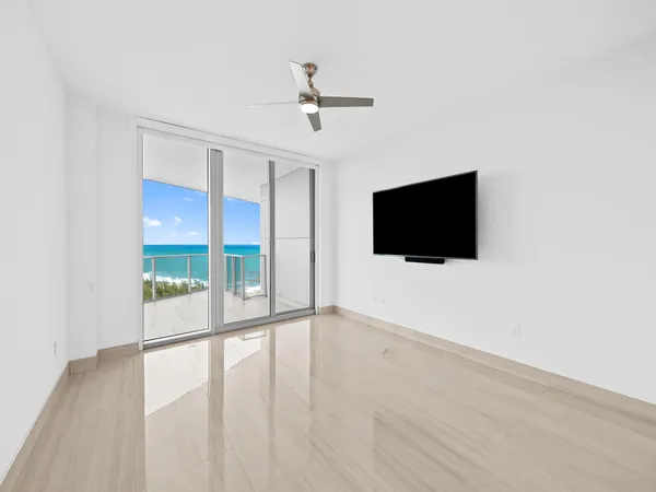 a view of an empty room with wooden floor and a flat screen tv