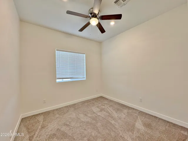 an empty room with a window and a fan