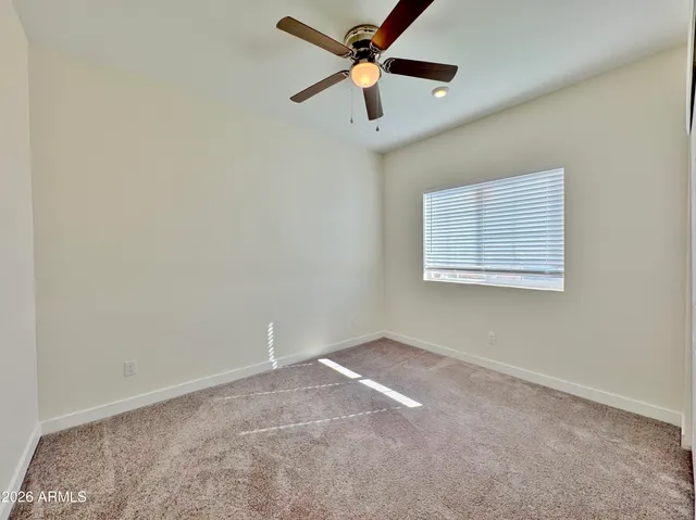 an empty room with a window and a fan