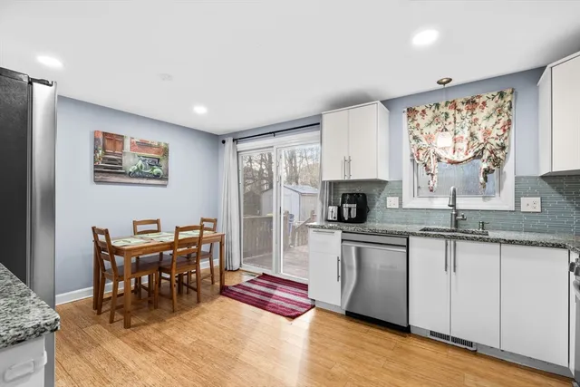 a kitchen with granite countertop a stove a sink a dining table and chairs with wooden floor