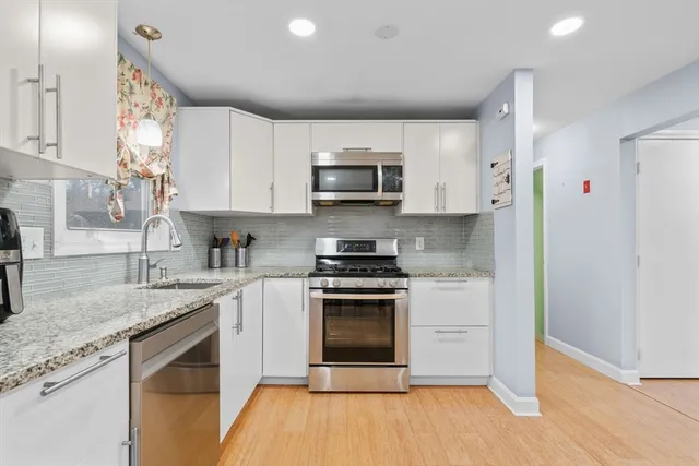 a kitchen with stainless steel appliances granite countertop a stove a sink and a microwave