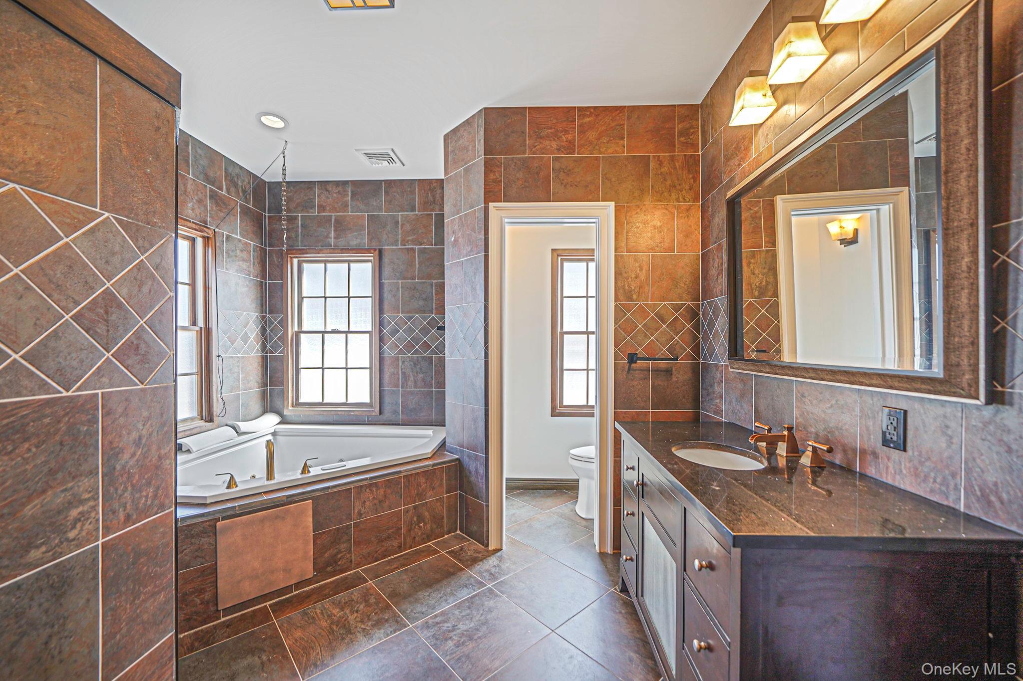 368 Main Street Setauket, NY 11733 - Photo 22 of 41 a bathroom with a double vanity sink a mirror and a bathtub