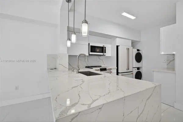 a large white kitchen with sink and refrigerator