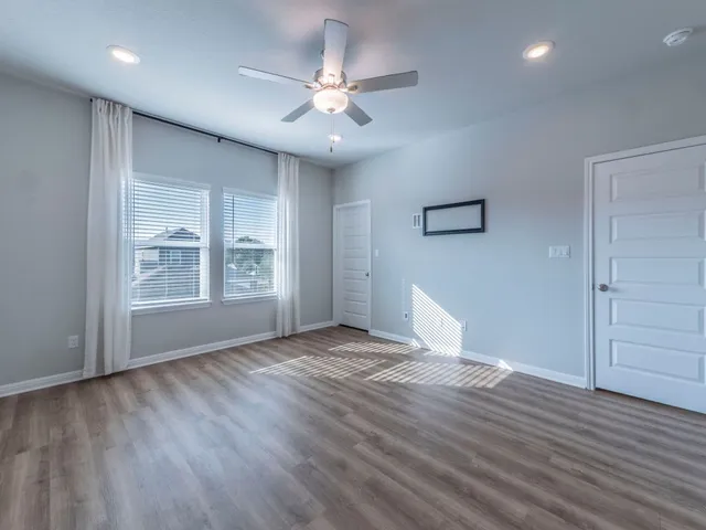 a view of an empty room with a window and wooden floor