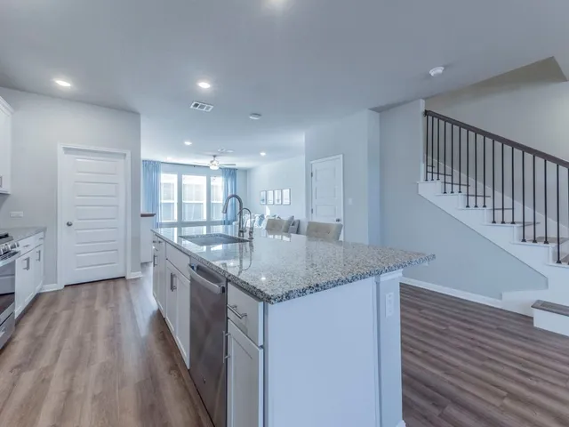 a kitchen with granite countertop a sink and wooden floor