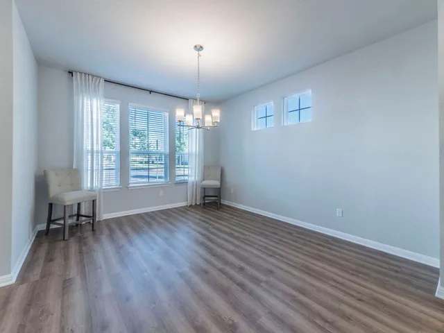 an empty room with wooden floor chandelier and windows