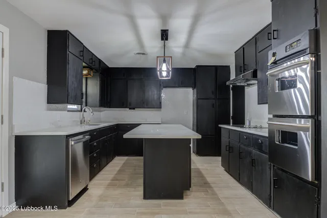 a kitchen with stainless steel appliances kitchen island granite countertop a refrigerator and a sink