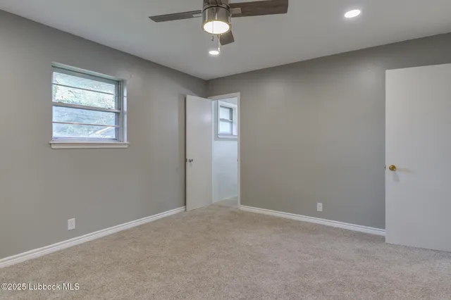 en empty room with windows and ceiling fan