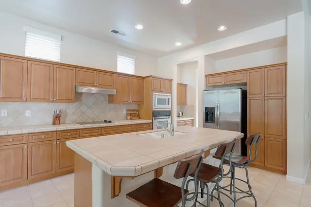 a kitchen with stainless steel appliances granite countertop a kitchen island a table and chairs in it