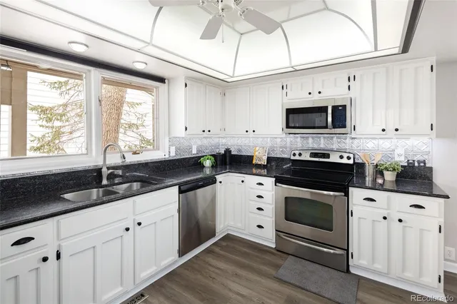 a kitchen with granite countertop white cabinets white stainless steel appliances and a sink