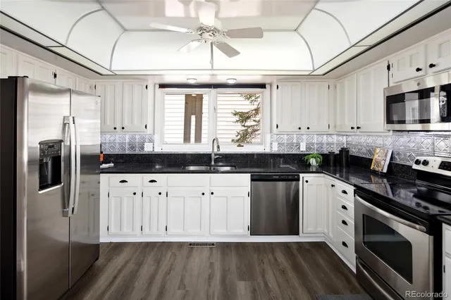 a kitchen with stainless steel appliances granite countertop a sink a stove and refrigerator