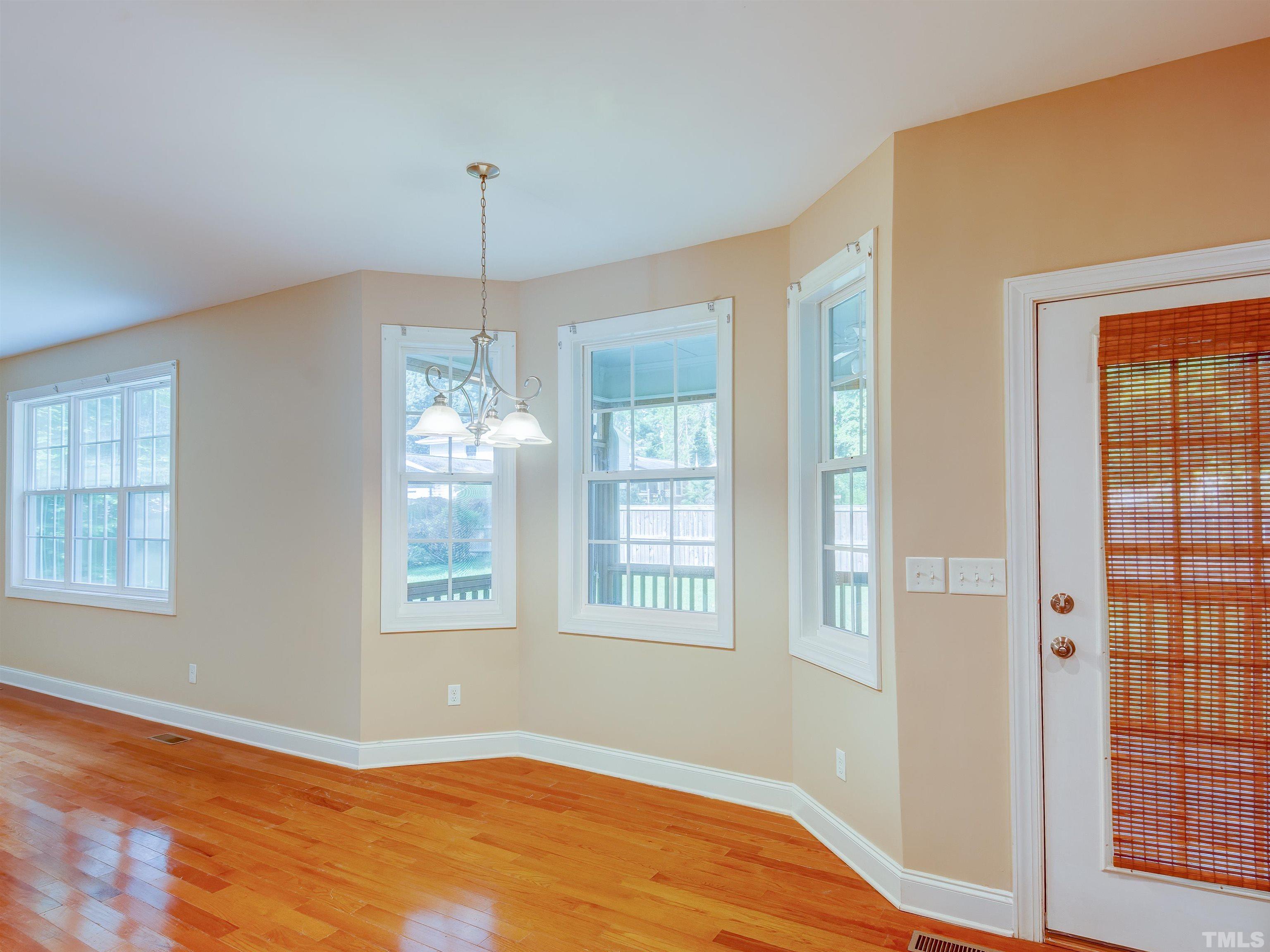 1104 Kingston Ridge Road Cary, NC 27511 - Photo 12 of 26 a view of an empty room with wooden floor and windows
