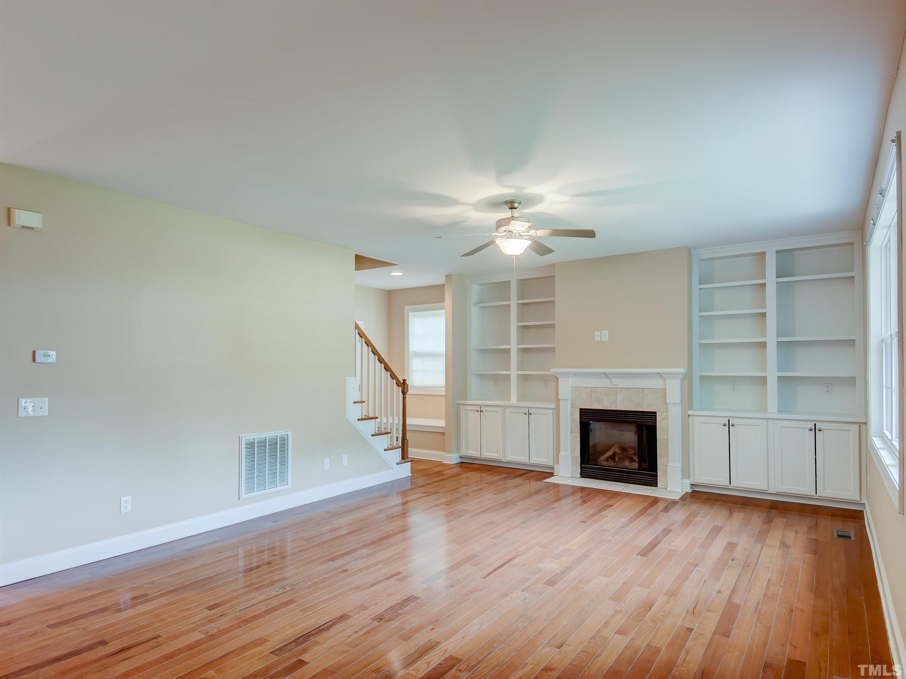 1104 Kingston Ridge Road Cary, NC 27511 - Photo 13 of 26 a view of an empty room with wooden floor fireplace and a window