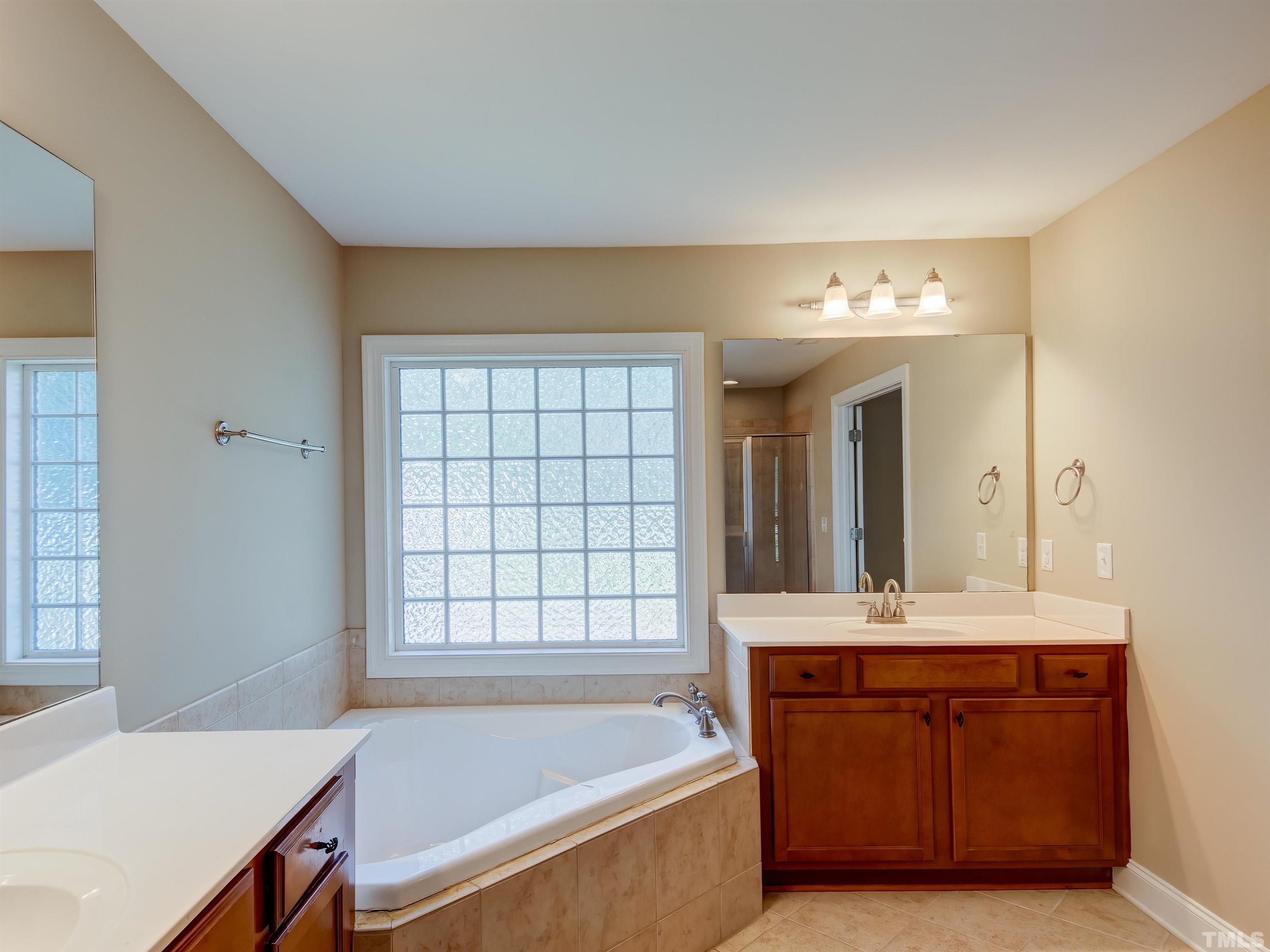 1104 Kingston Ridge Road Cary, NC 27511 - Photo 20 of 26 a bathroom with a bathtub sink and mirror