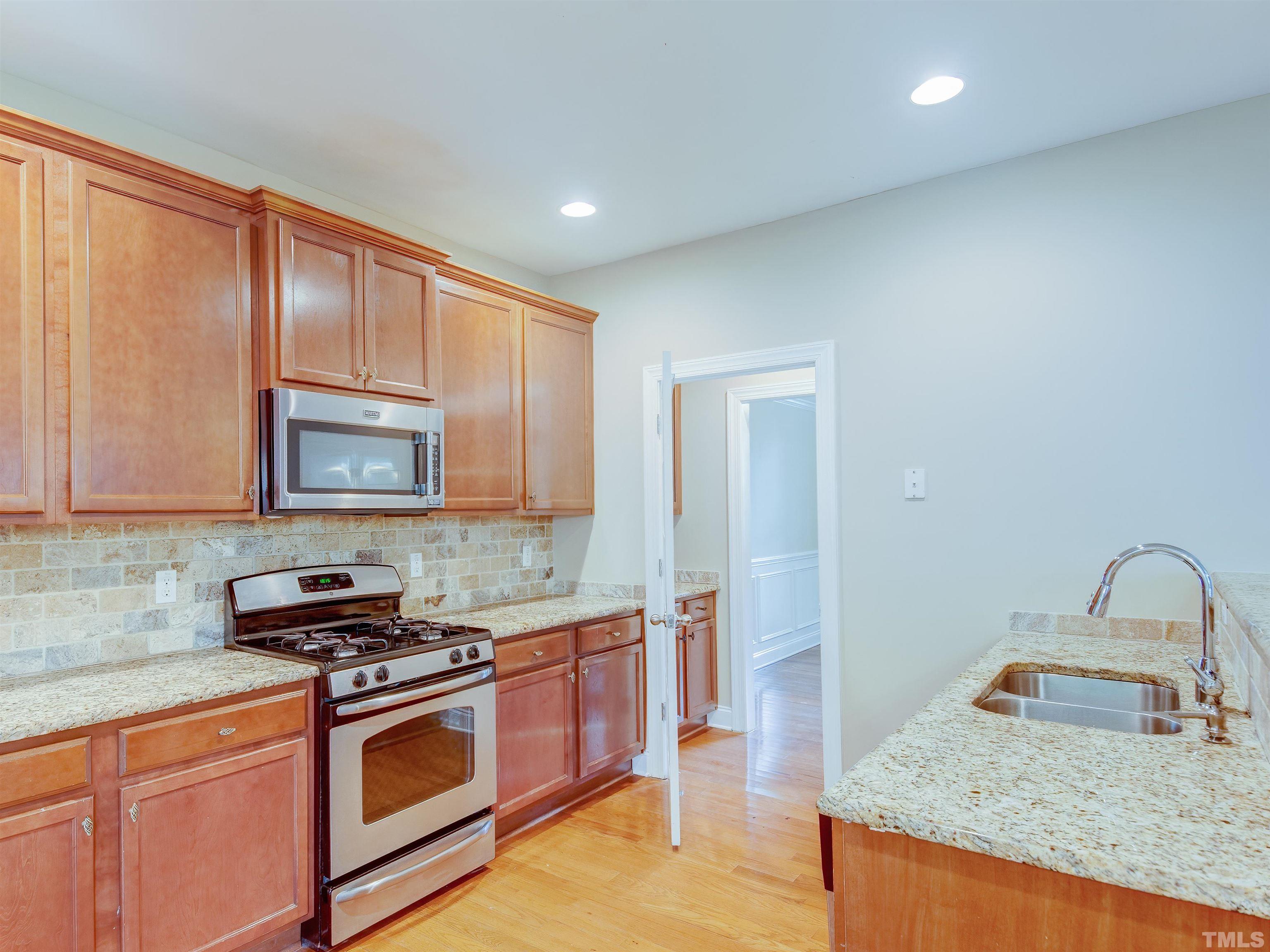 1104 Kingston Ridge Road Cary, NC 27511 - Photo 9 of 26 a kitchen with granite countertop a sink a stove and cabinets