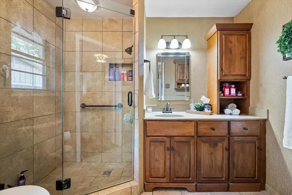 a bathroom with a granite countertop sink a mirror and shower