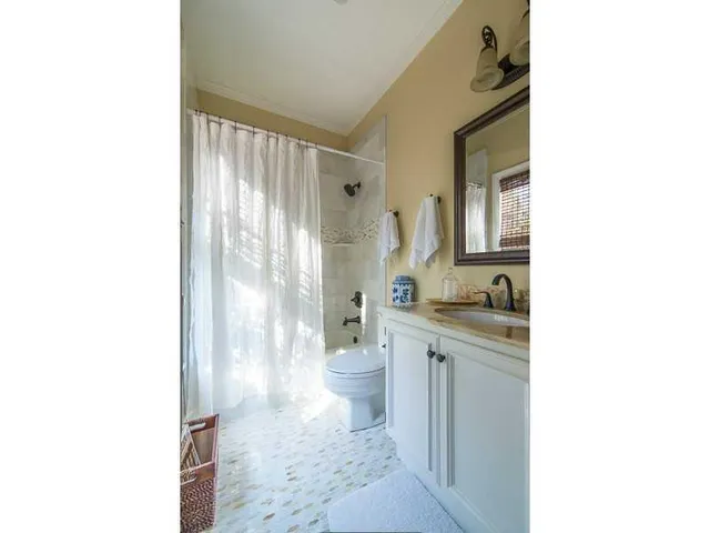 a bathroom with a granite countertop sink a toilet a mirror and shower
