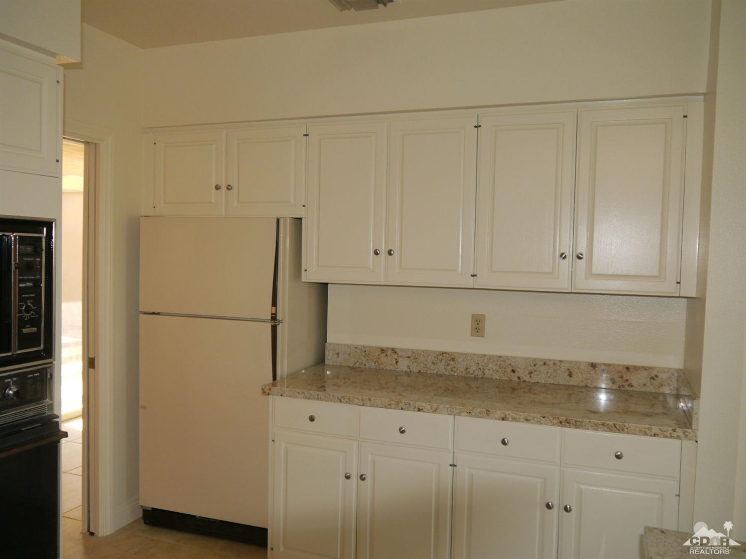46330 Dove Road Indian Wells, CA 92210 - Photo 9 of 25 a kitchen with white cabinets and refrigerator