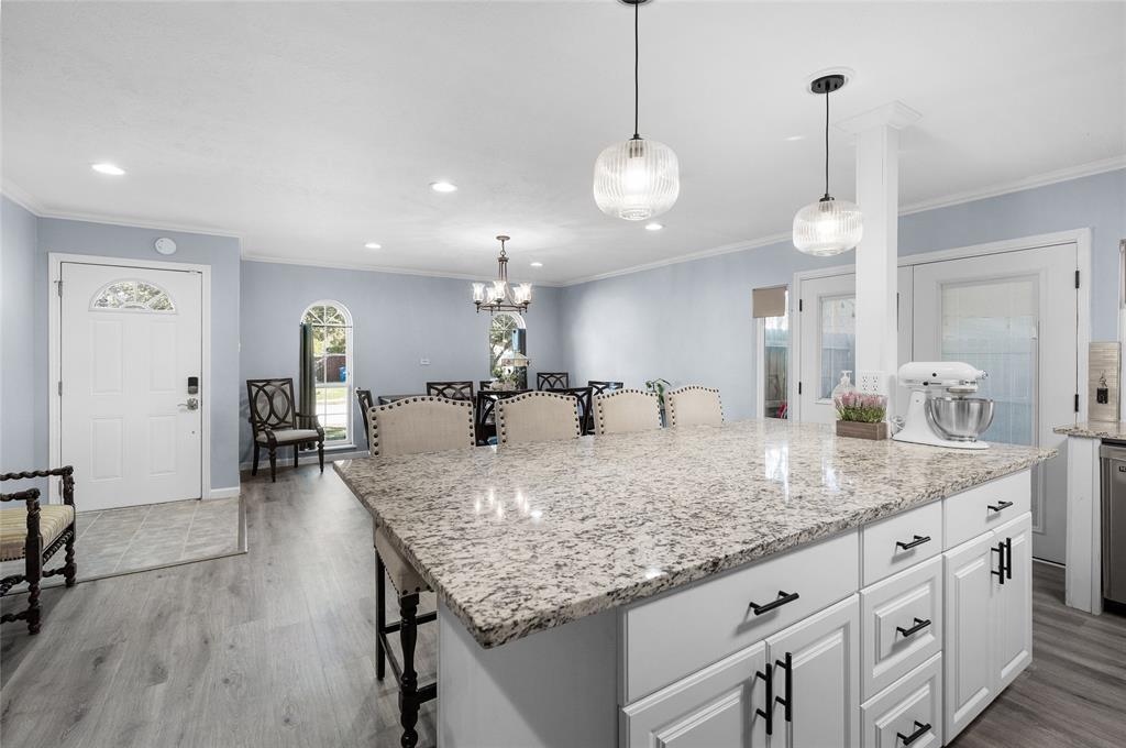 2038 Rose Hill Road Carrollton, TX 75007 - Photo 12 of 35 a large kitchen with granite countertop a stove a sink a dining table and chairs with wooden floor