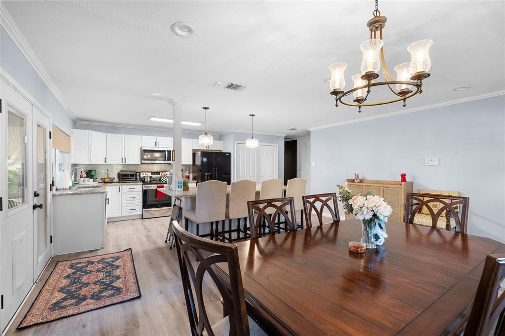 2038 Rose Hill Road Carrollton, TX 75007 - Photo 6 of 35 a kitchen and a dining room with wooden floor a chandelier a wooden table and chairs