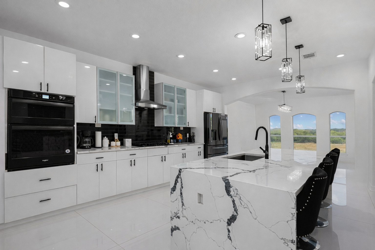 507 Rawhide Road Seguin, TX 78155 - Photo 13 of 40 Kitchen with a large island, light stone countertops, arched walkways, and white cabinets