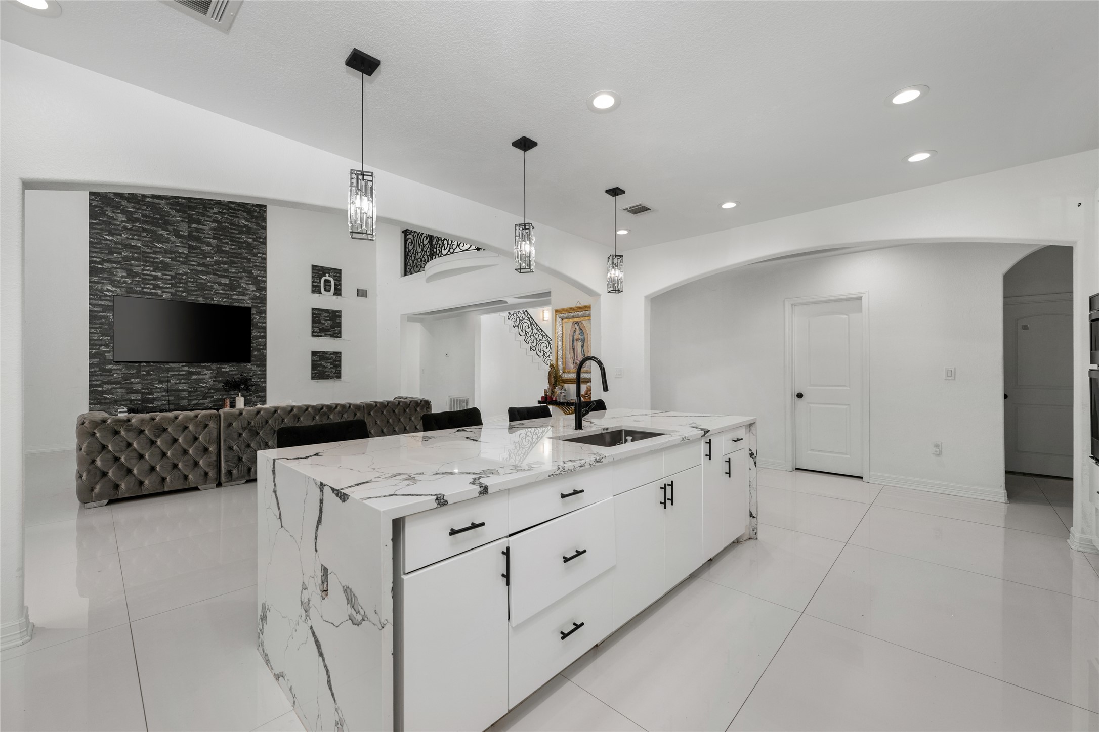 507 Rawhide Road Seguin, TX 78155 - Photo 39 of 40 Kitchen with white cabinets, arched walkways, open floor plan, a center island with sink, and light stone counters