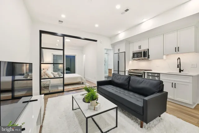 a living room with stainless steel appliances furniture and a kitchen view