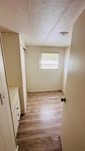 a view of an empty room with wooden floor and stairs